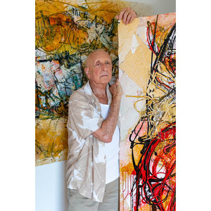Artist John Berrick standing with his artworks