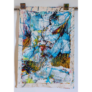 Abstract art piece with colorful splashes on a textured surface, mounted on a white wall. By John Berrick.
