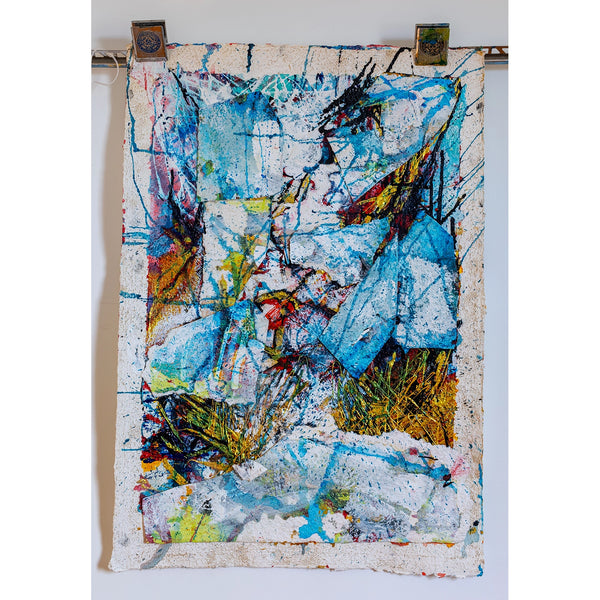 Abstract art piece with colorful splashes on a textured surface, mounted on a white wall. By John Berrick.